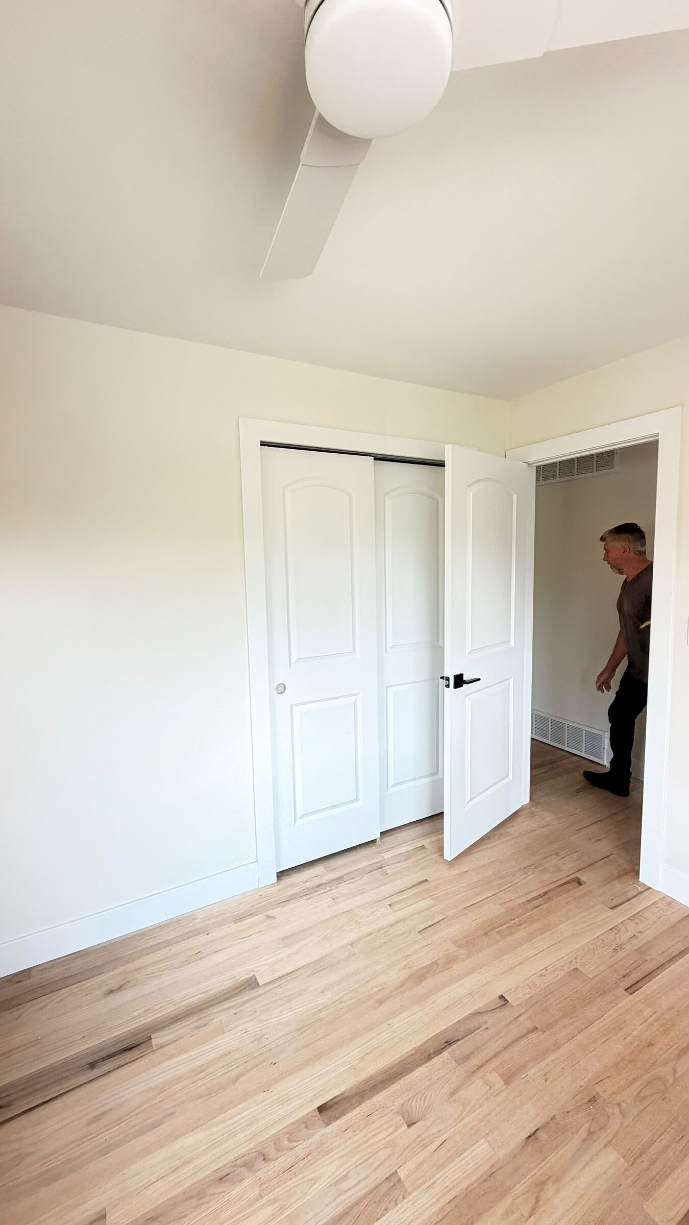 Bedroom with closet doors open, hallway and second bedroom visible beyond
