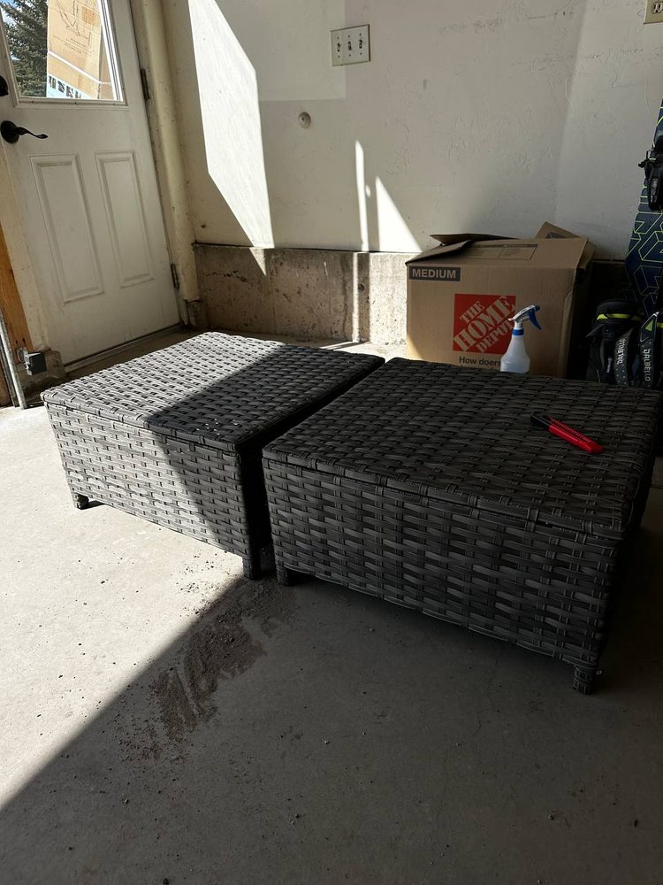 Two finished gray wicker patio ottomans assembled and set in a garage