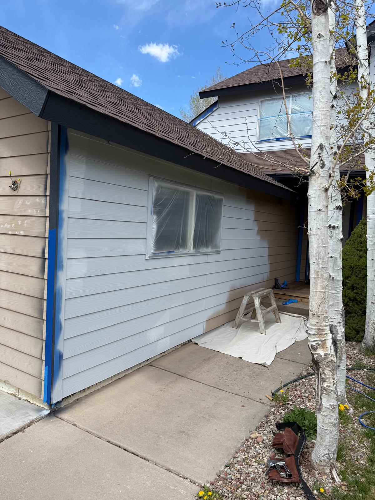 Half-painted siding showing the new light gray finish next to the original tan