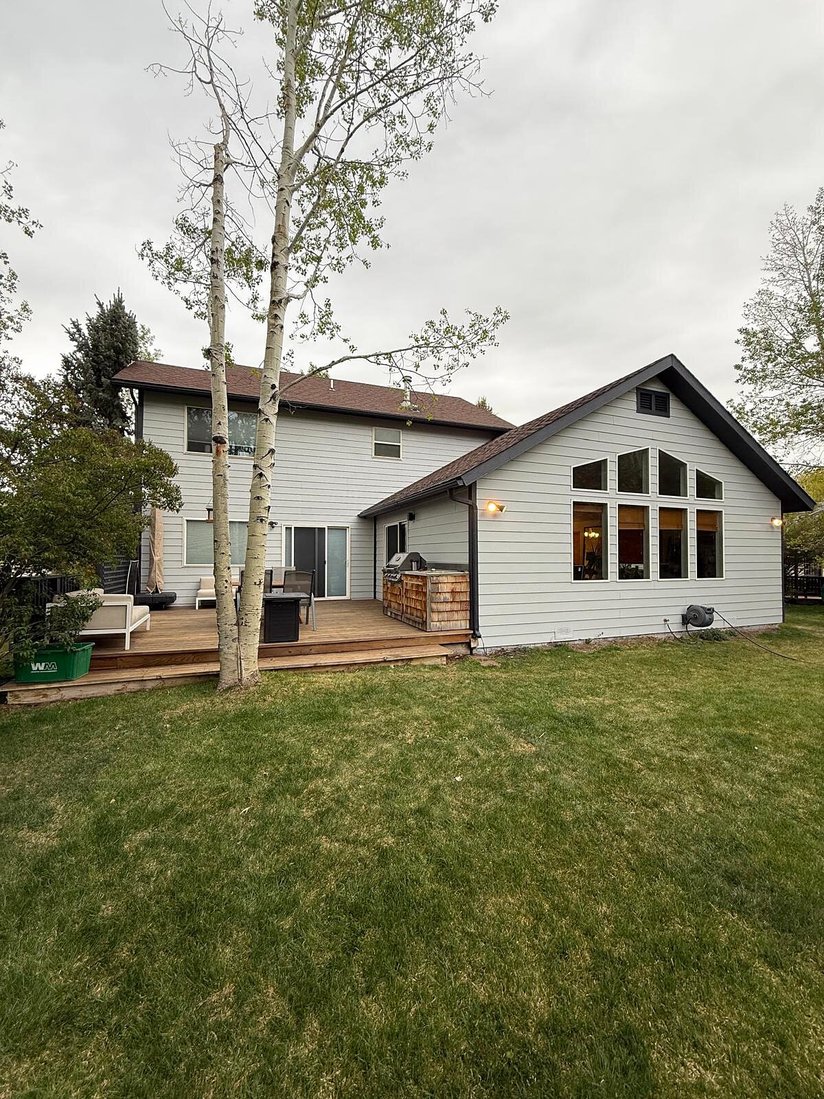 Finished back exterior with a vaulted great room addition and wood deck with built-in grill station