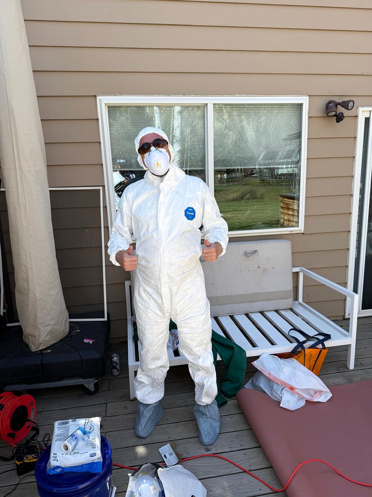 Painter suited up in a Tyvek coverall, respirator, and booties before starting exterior spray work