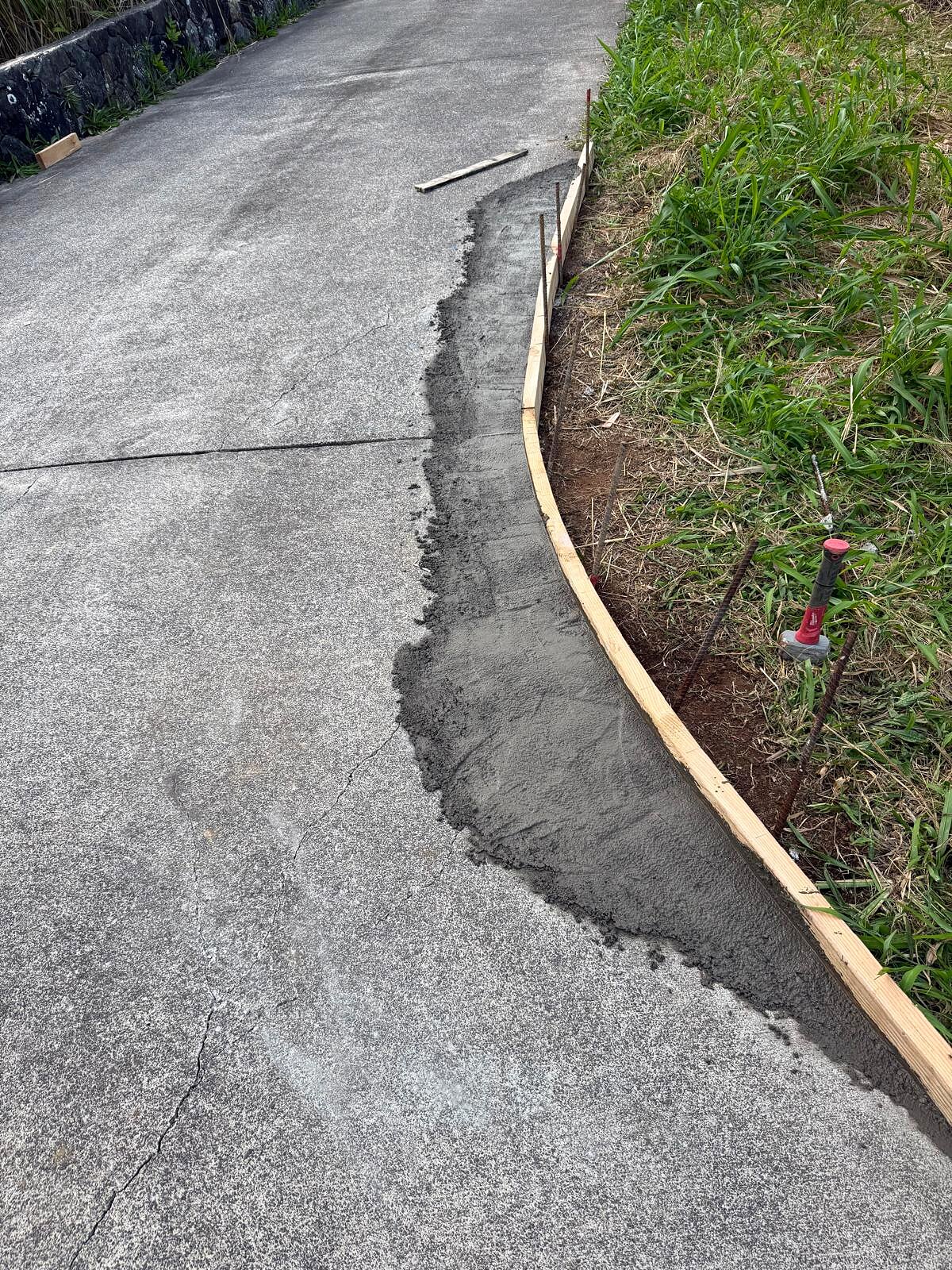Closer view of fresh wet concrete poured into the wood curb forms along the roadside edge