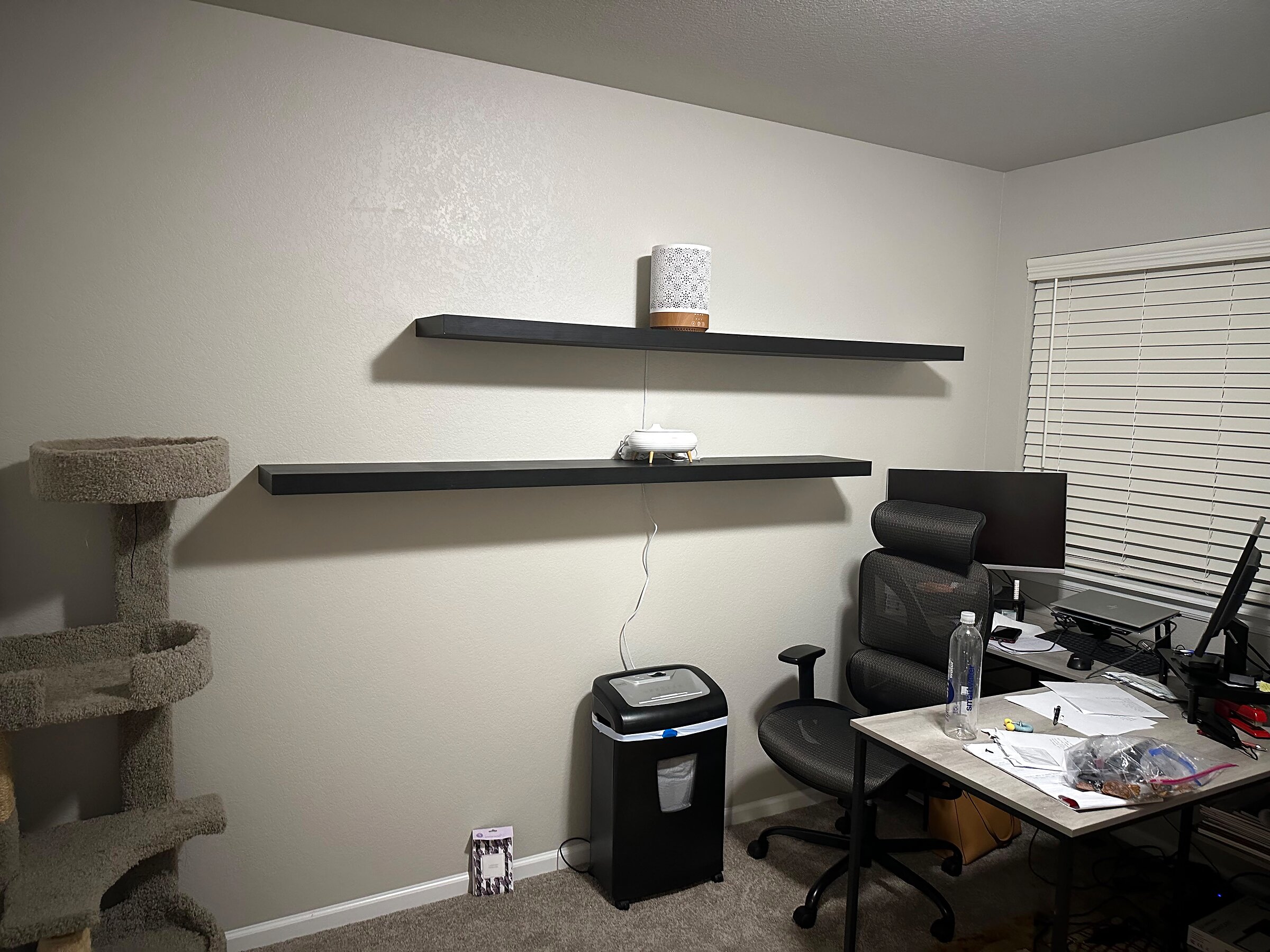 Pair of black floating shelves mounted level above a home office desk