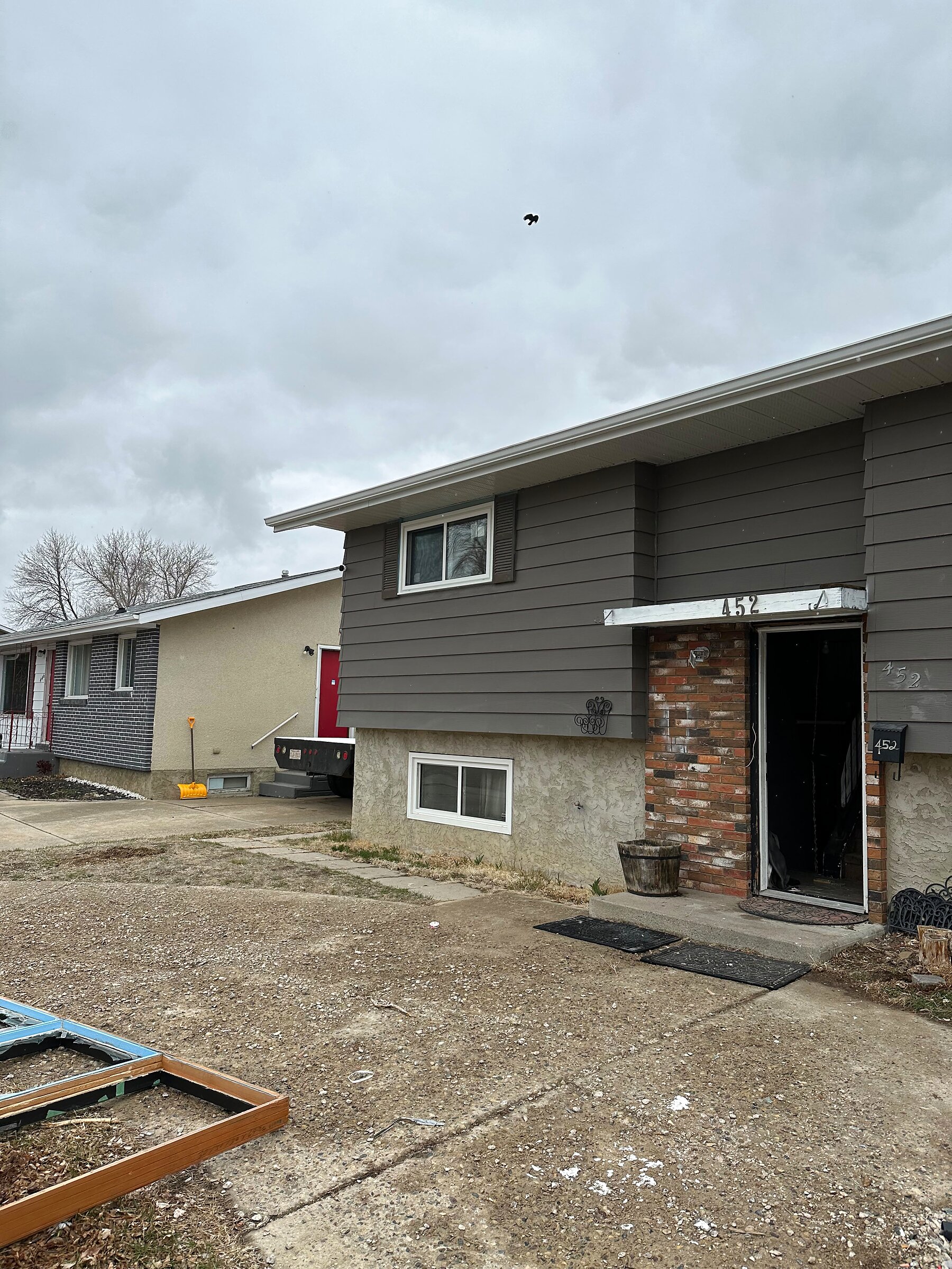 Gray-sided home with a large new picture window and dark shutters above a walkout basement window