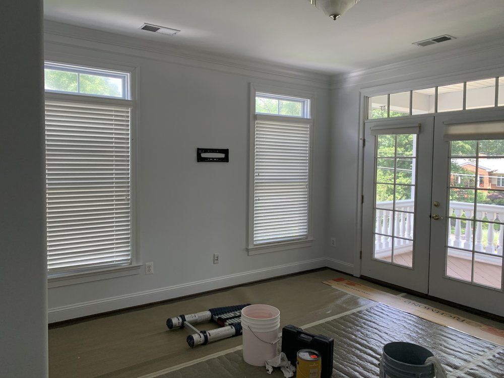 Living room masked with floor protection, rollers and paint buckets staged before an interior repaint