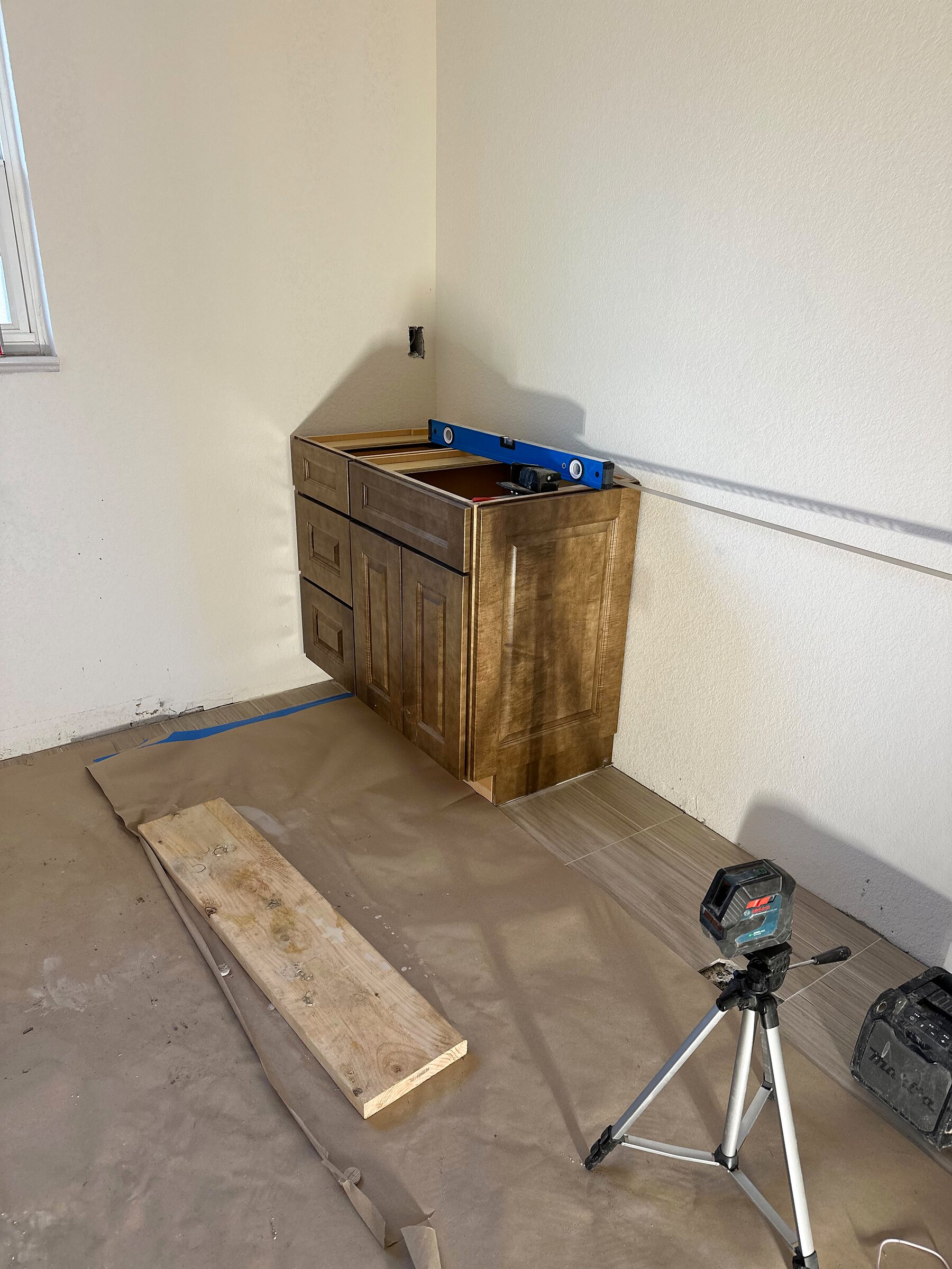 Corner bathroom vanity cabinet being installed and leveled