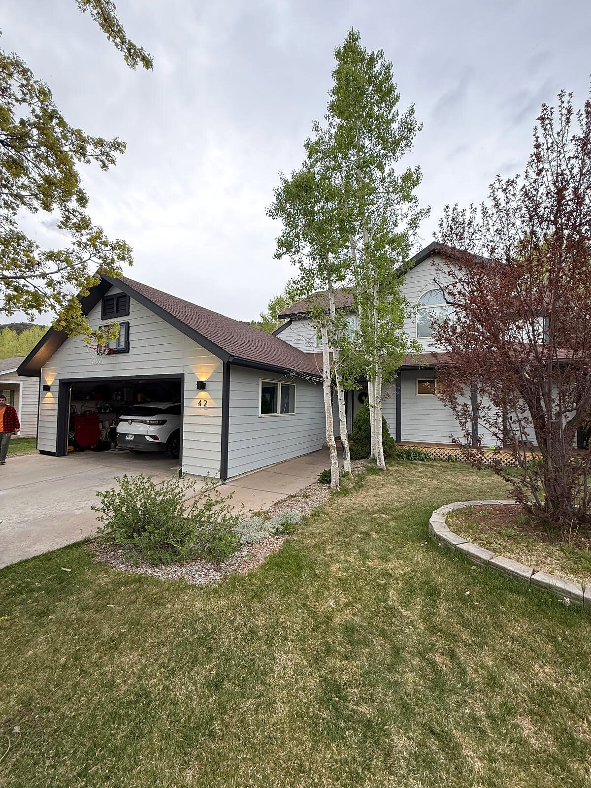 Finished front exterior repaint of a two-story mountain-area home with mature aspen trees