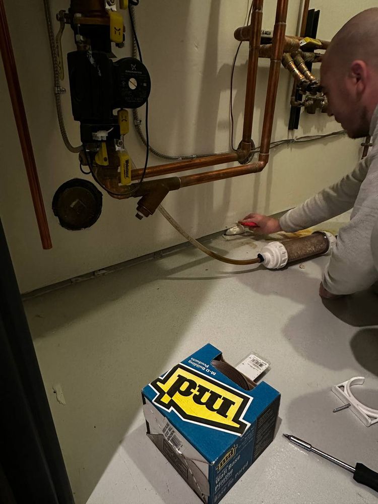 Connecting a water treatment tank to copper supply lines beside a circulator pump in a utility room
