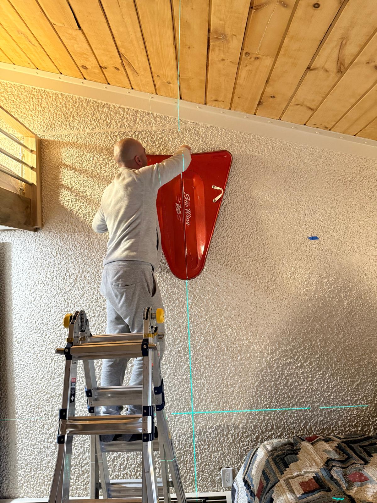 Vintage red sled hung level on a stucco wall below a wood plank ceiling