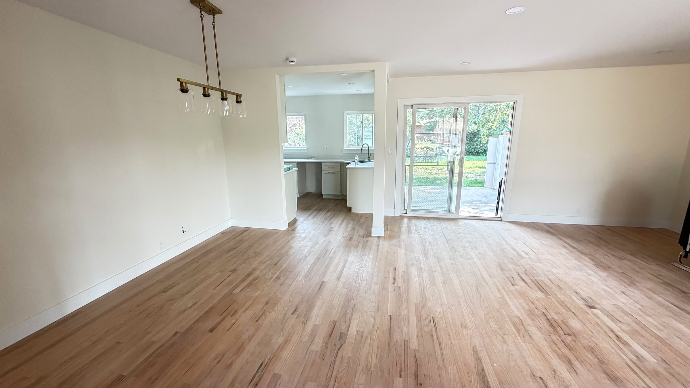 Open-concept living and kitchen area with refinished hardwood floors and a slider to the backyard