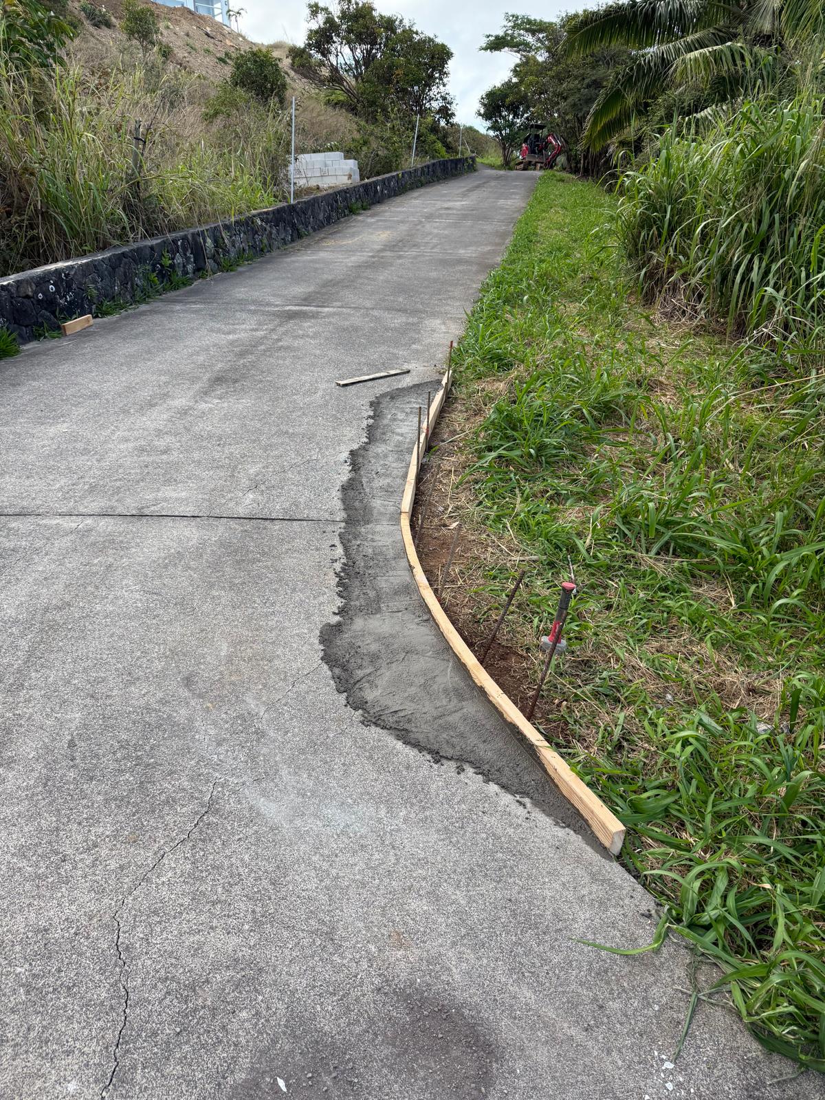 Full run of a new concrete curb extending the driveway edge with wood forms still in place