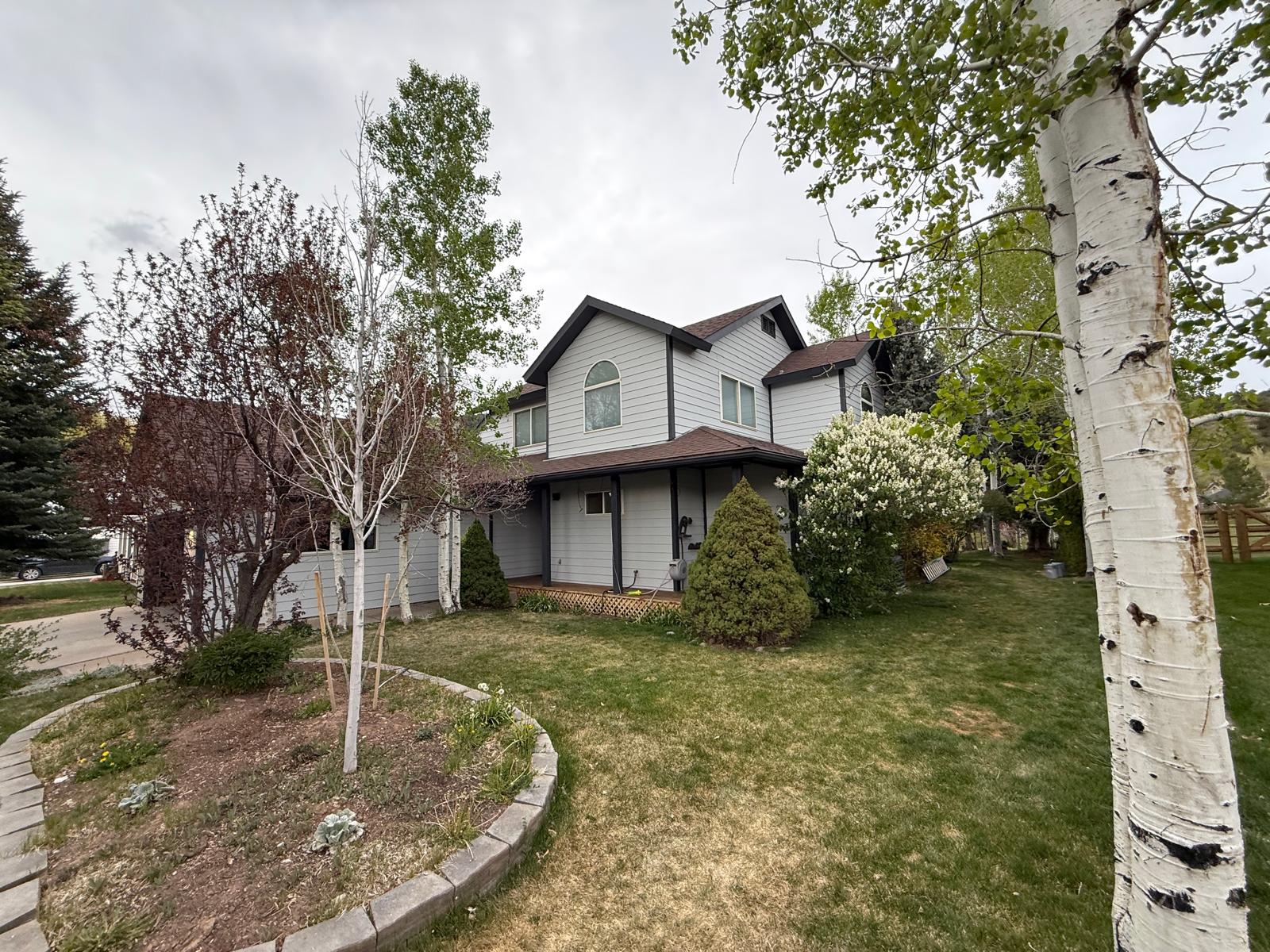 Front elevation of the finished home showing fresh light gray siding and crisp dark trim