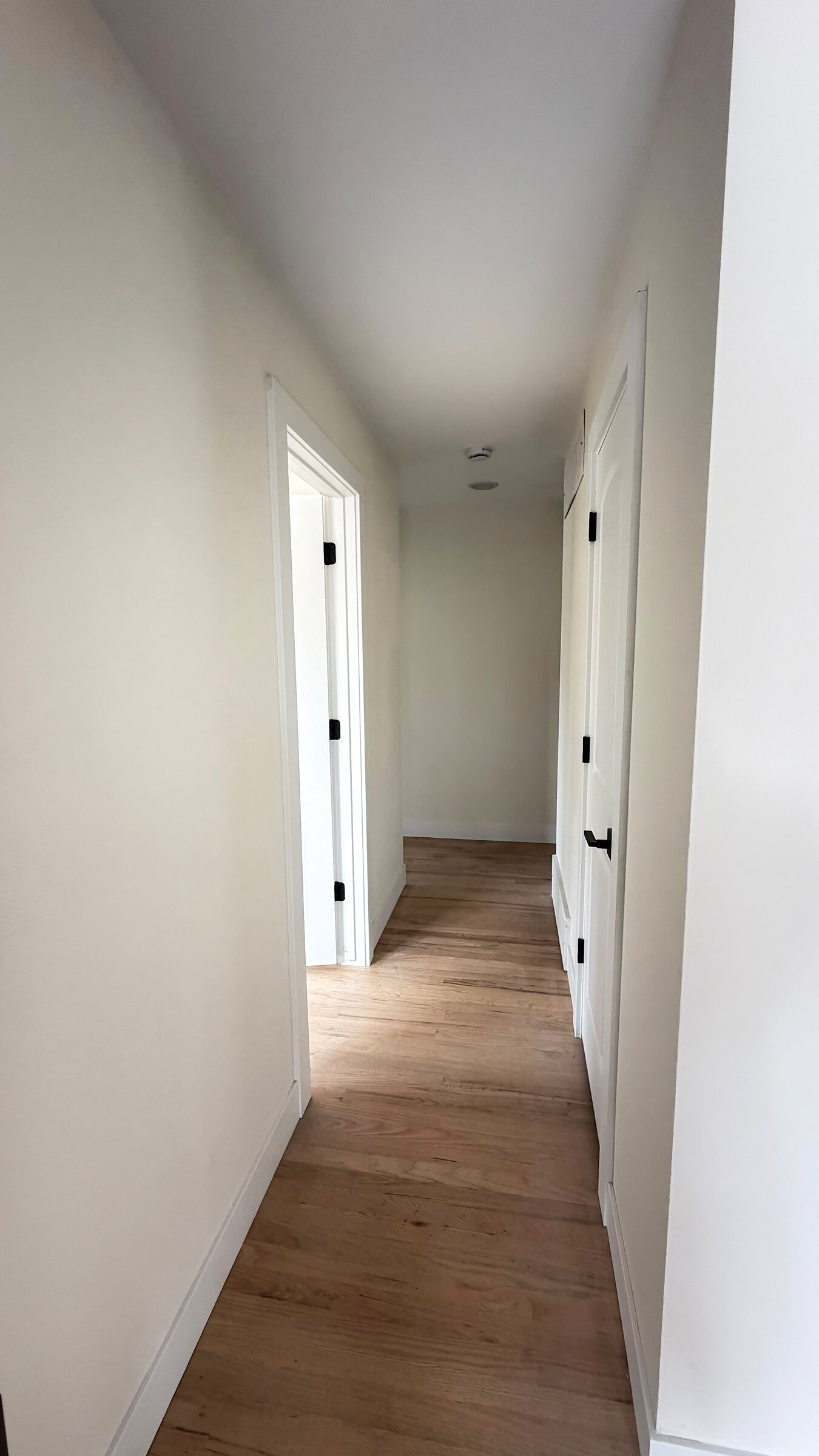 Hallway with two bedroom doors and freshly refinished hardwood flooring