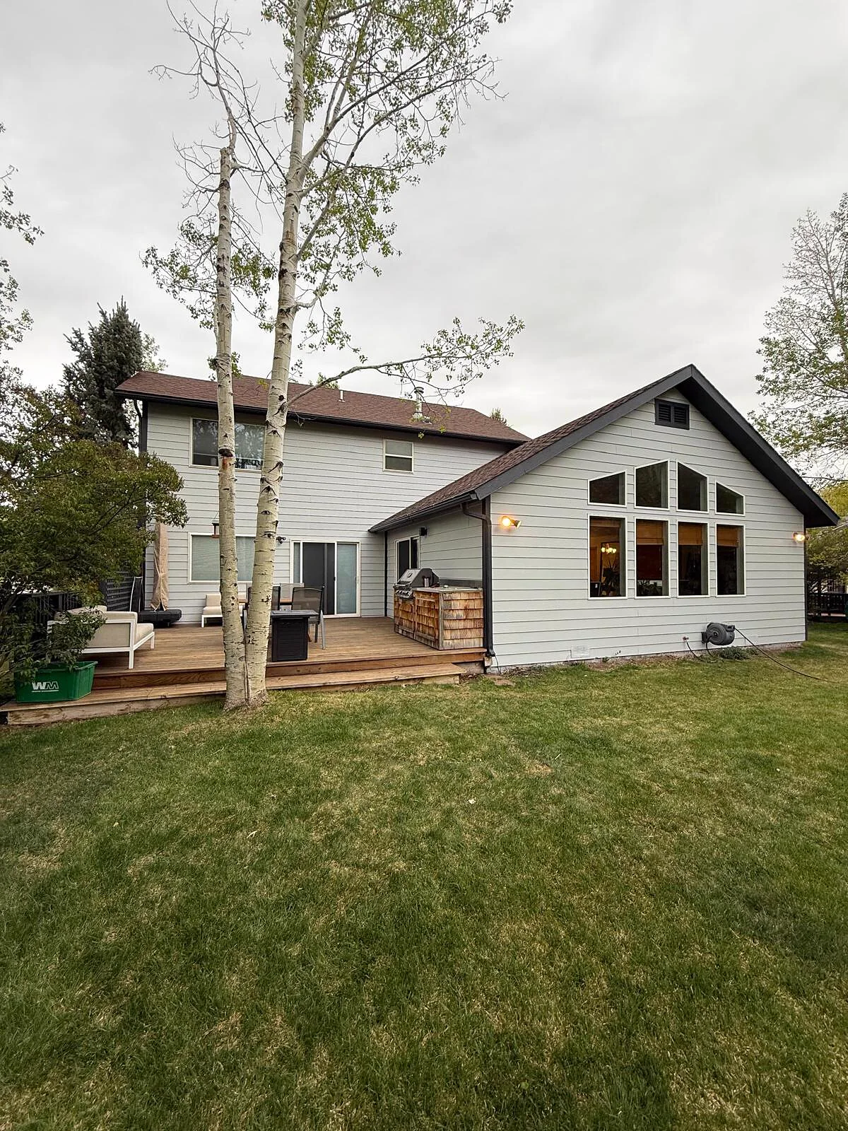 Finished back exterior with a vaulted great room addition and wood deck with built-in grill station