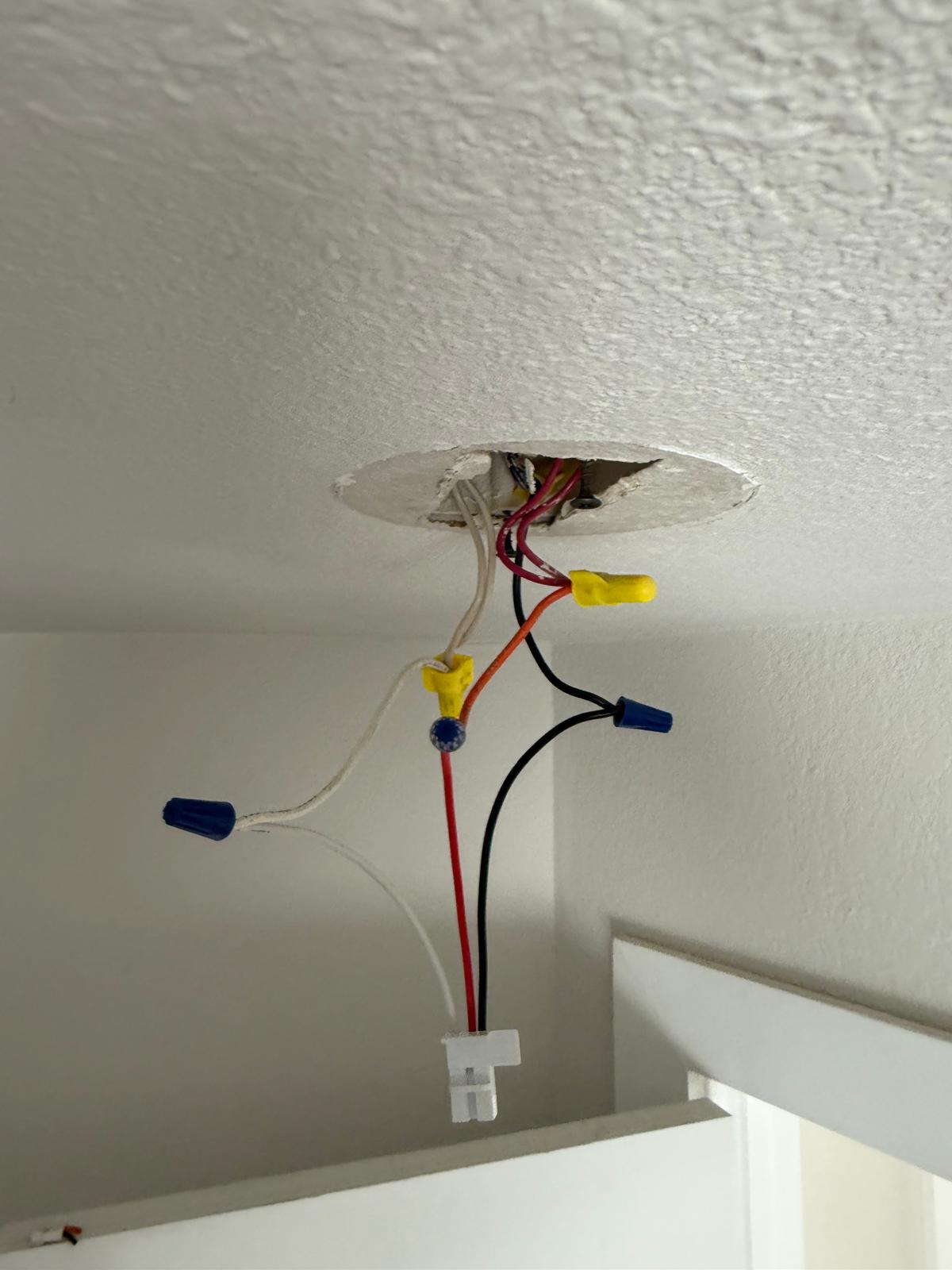 Close view of a ceiling junction box with wire nuts and a fixture harness prepped for install