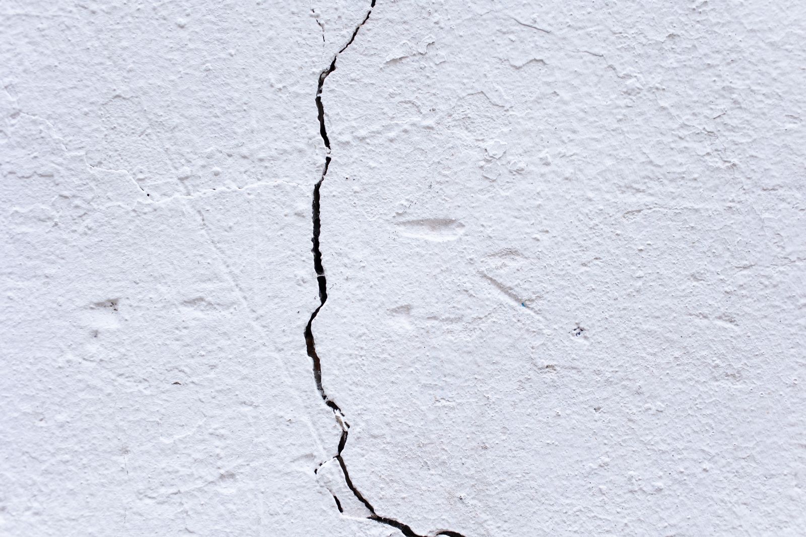 Close-up texture of a hairline crack in a painted plaster wall