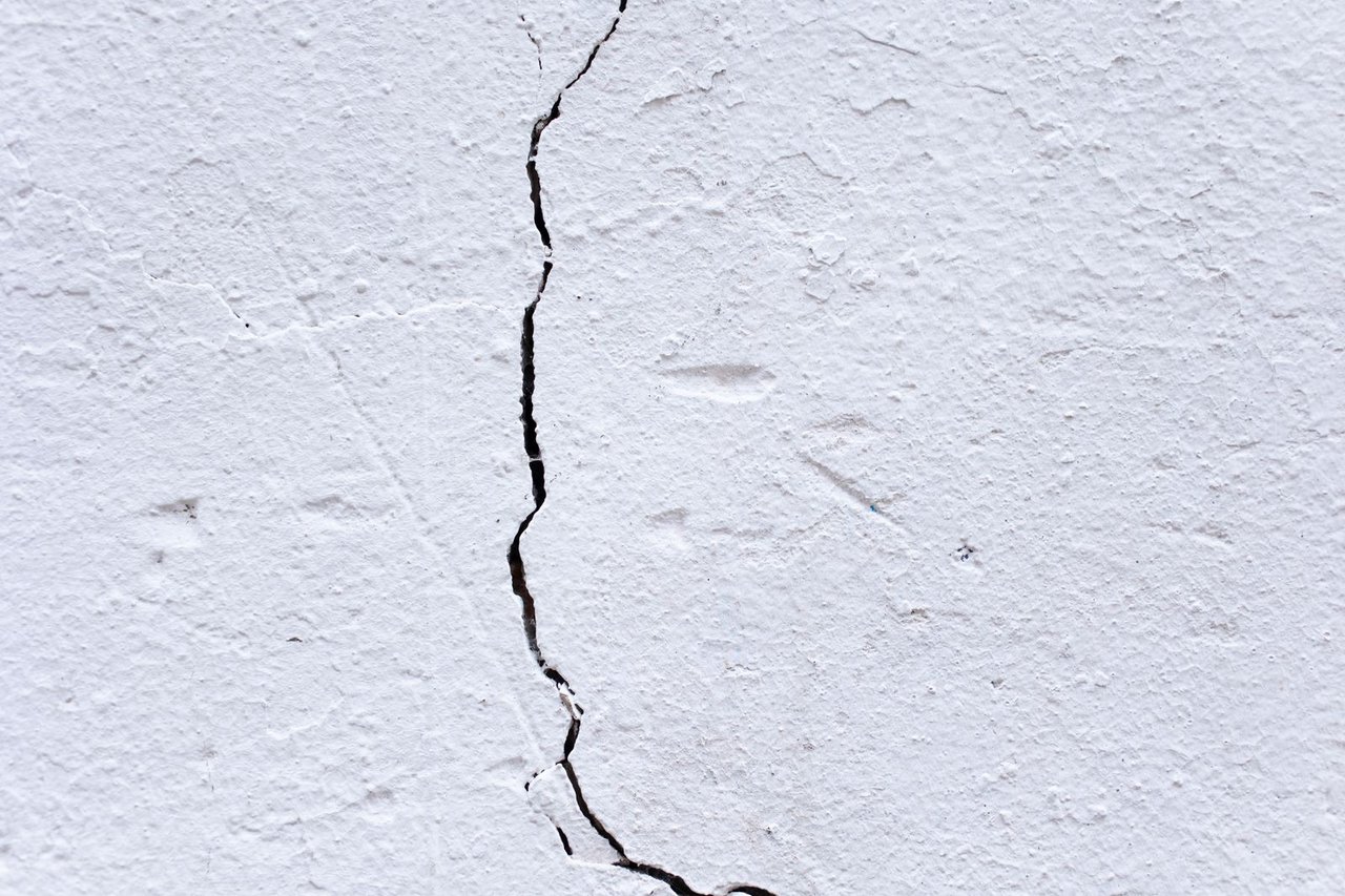 Close-up texture of a hairline crack in a painted plaster wall