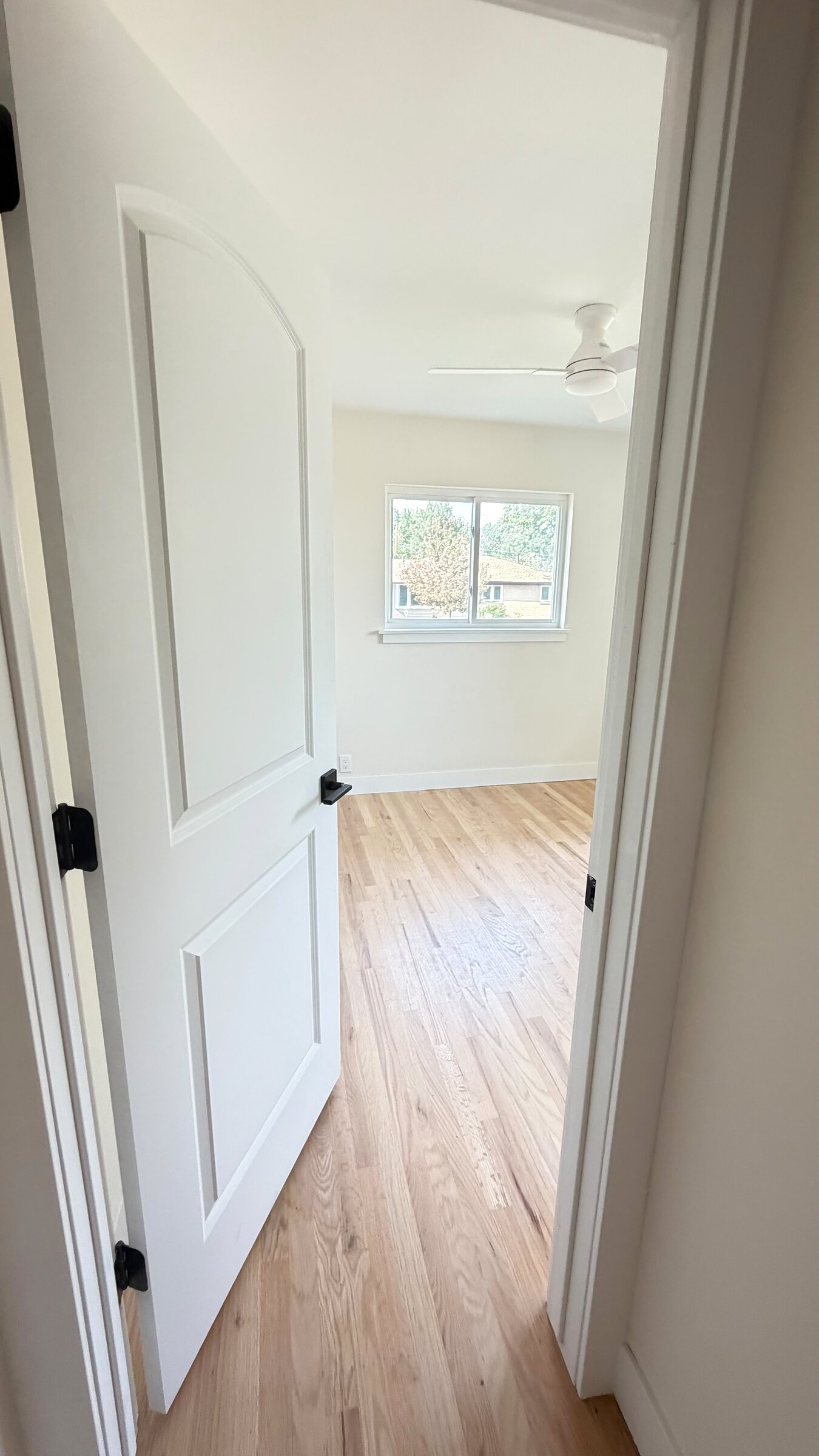 View into a finished bedroom with refinished hardwood floors and a ceiling fan