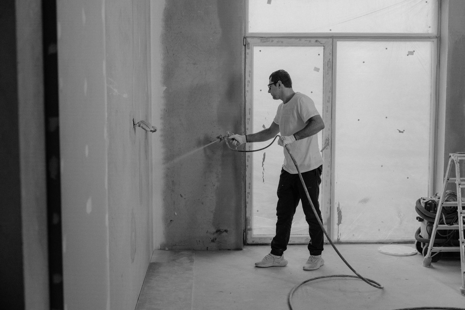 Painter spraying a smooth coat across an interior wall