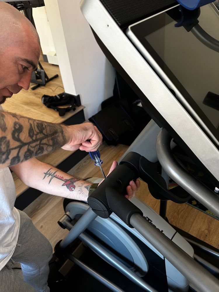 Technician driving screws into the console arm of a treadmill during assembly