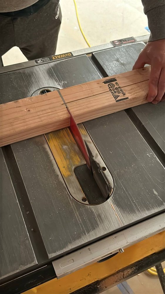 Technician ripping a board on a table saw during a carpentry job