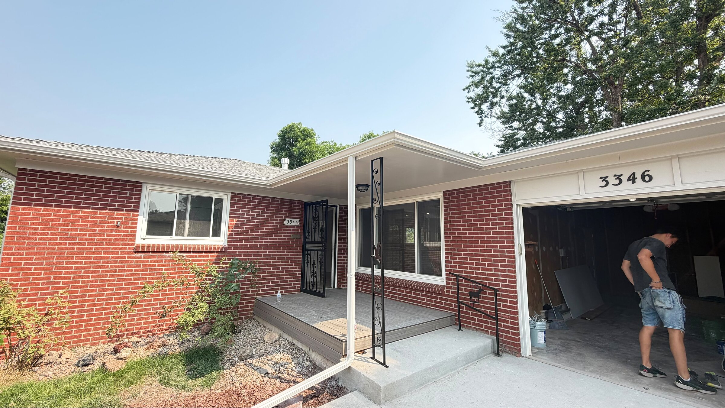 Brick ranch home mid-renovation with a new covered entry, security door, and open garage