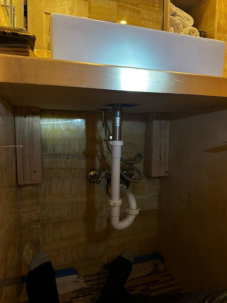Under-sink plumbing with P-trap and supply lines in a wood vanity cabinet