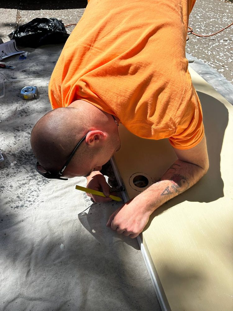 Marking a sink cutout line on a laminate countertop with a pencil and straightedge outdoors
