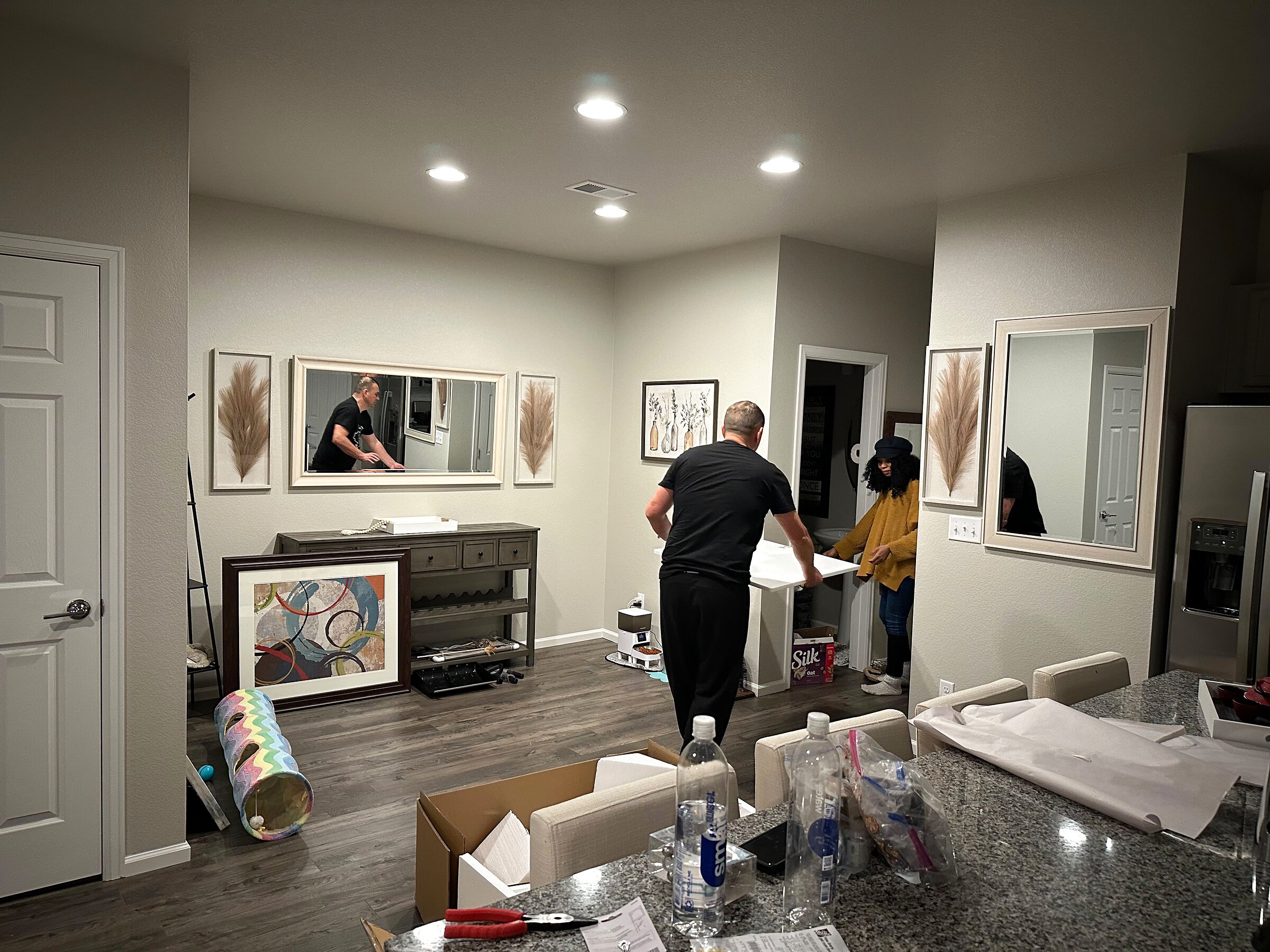 Two installers fitting a white floating console shelf into a kitchen pass-through opening
