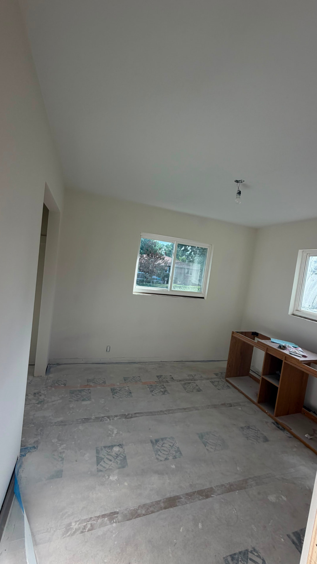 Unfinished interior during renovation with bare concrete floor, protective paper covering and a partially dismantled cabinet