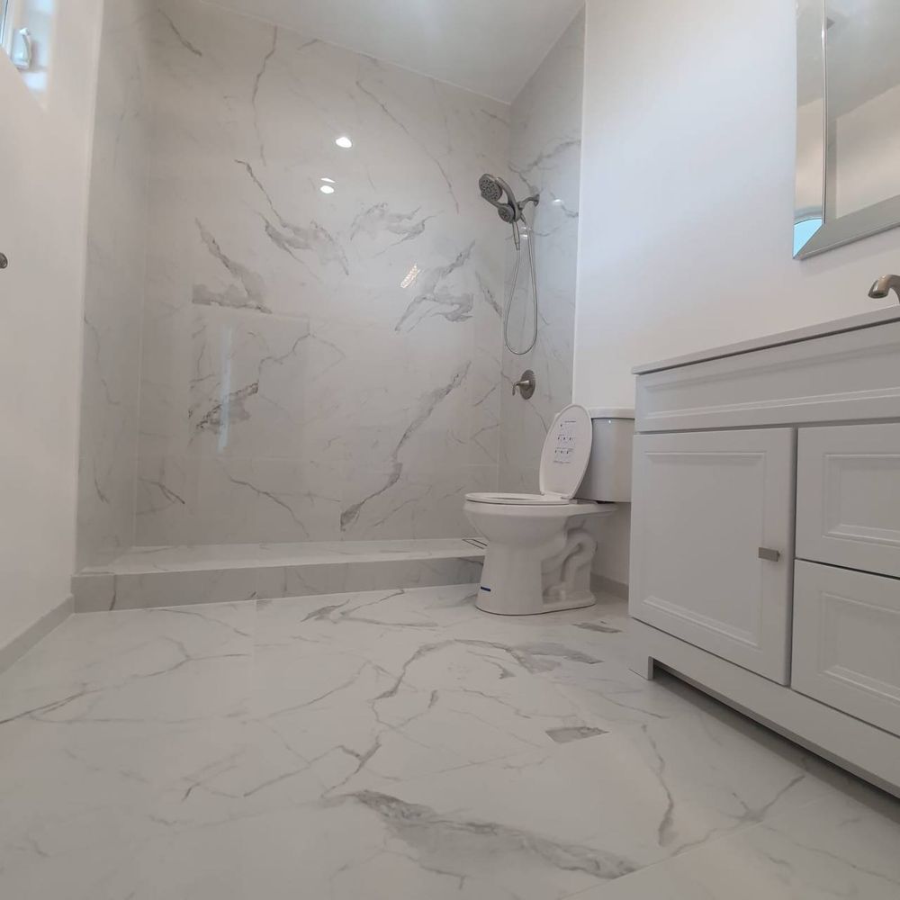 Marble-look tiled walk-in shower with built-in bench and matching tile floor in a finished bathroom