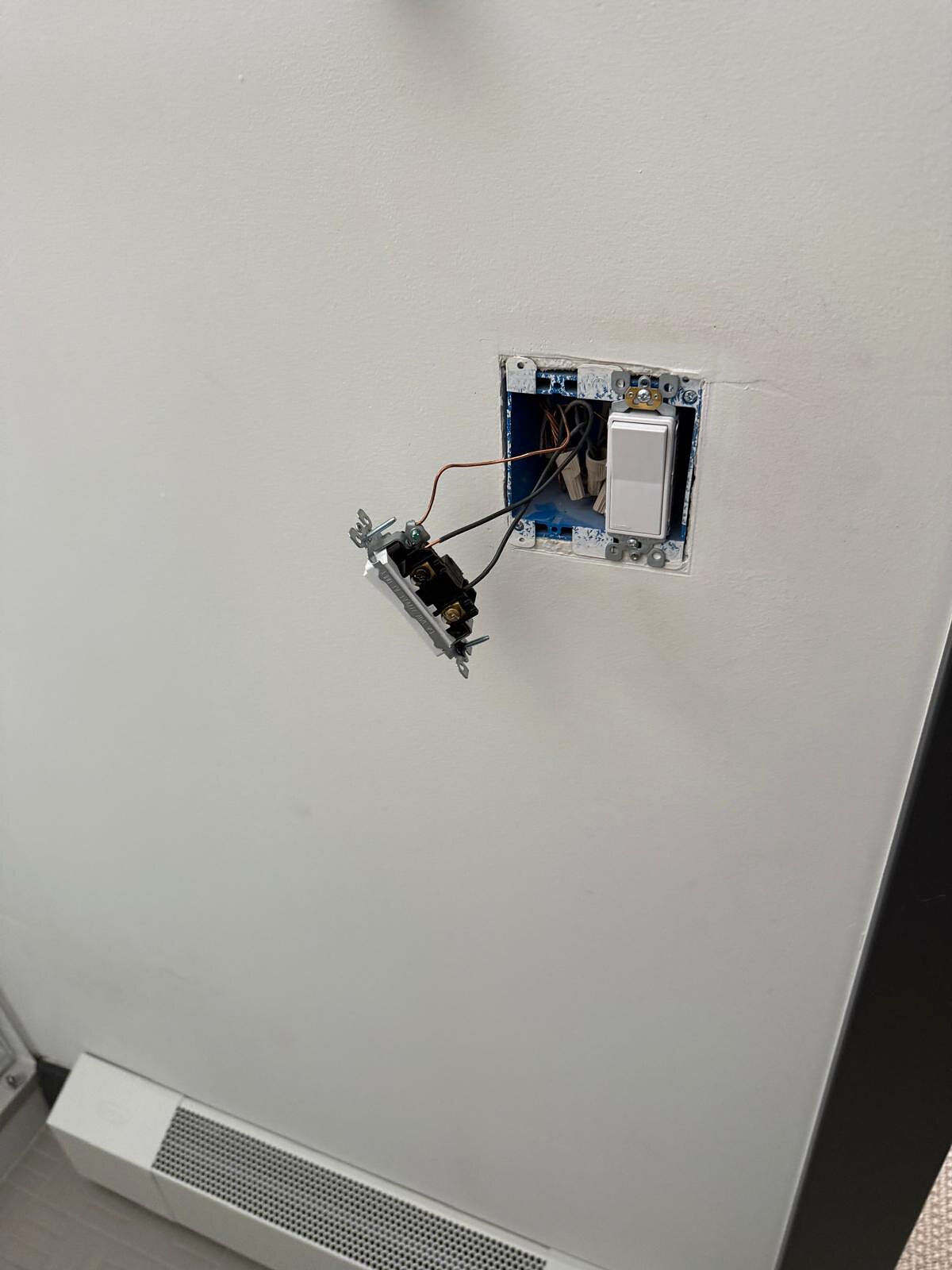 Open switch box with wiring exposed, new switch partly connected before the second device and cover plate go in
