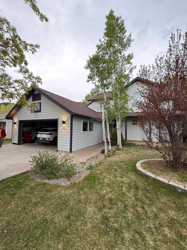 Finished front exterior repaint of a two-story mountain-area home with mature aspen trees