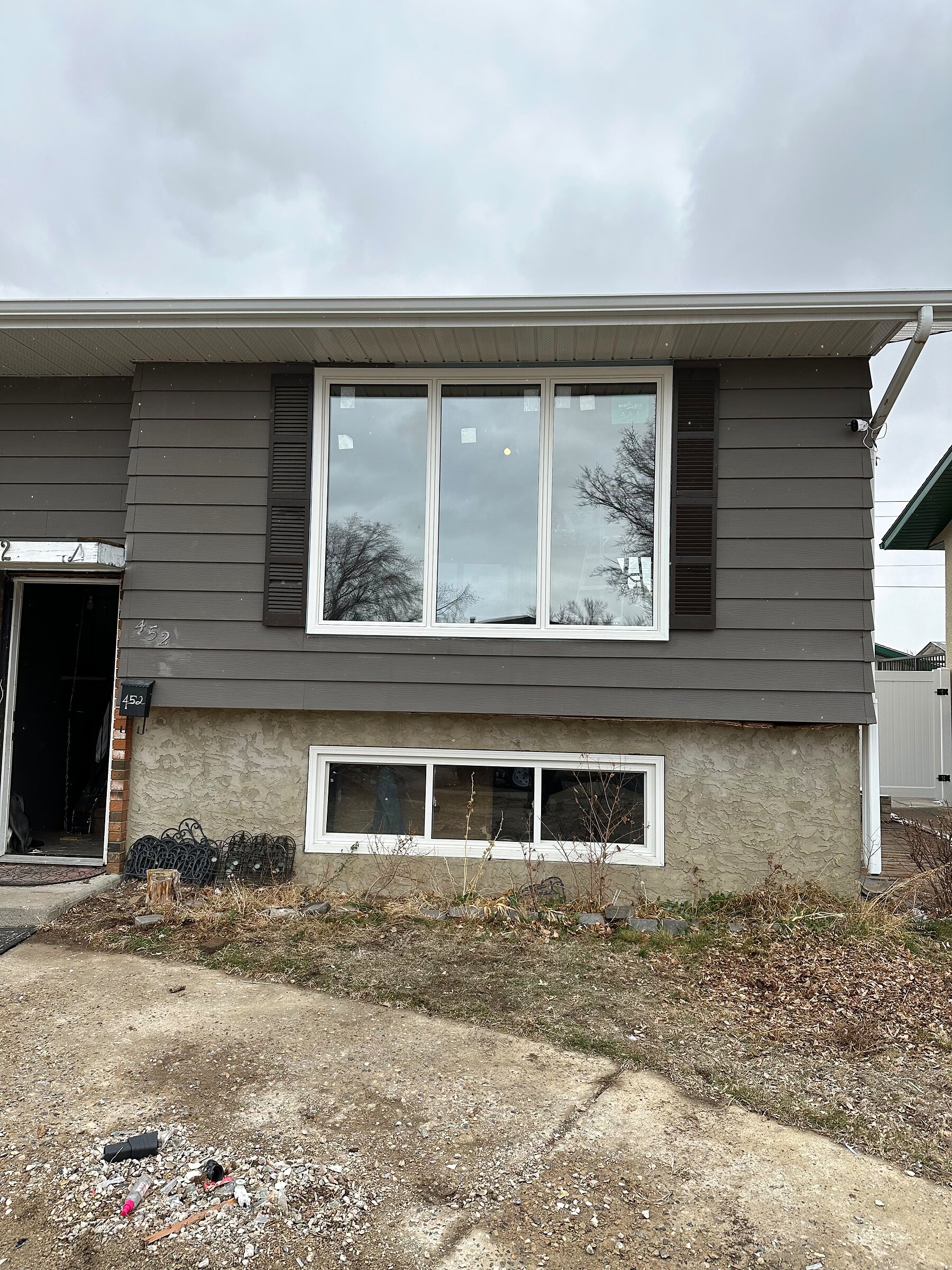 Closer view of a new wide picture window flanked by dark shutters