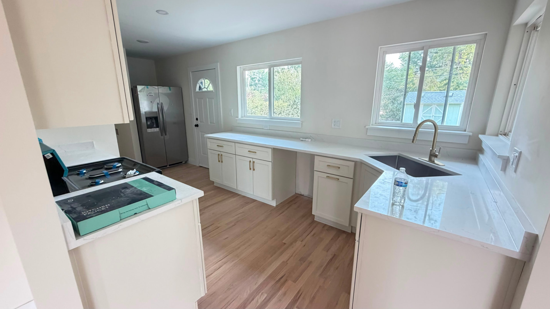 Finished kitchen with white cabinets, new countertops and hardwood flooring