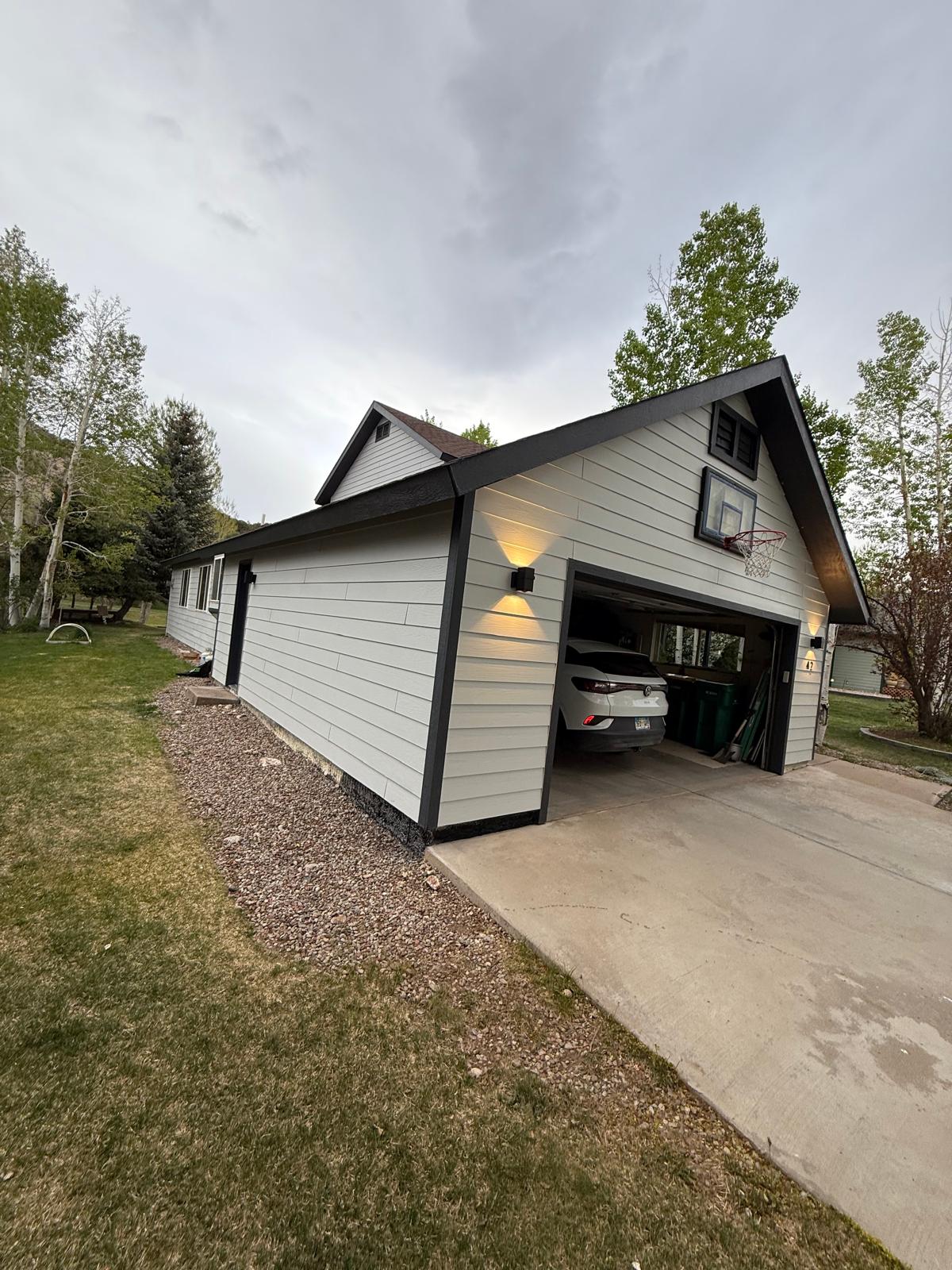 Side wall of the repainted garage showing even lap siding coverage and dark corner trim