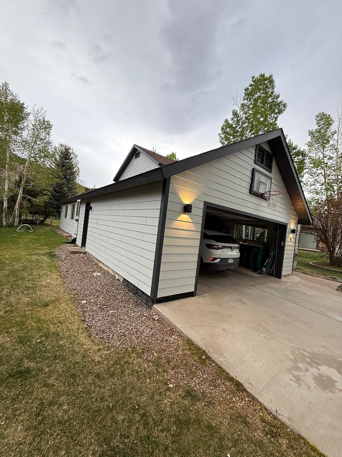 Finished two-car garage exterior with new paint, evening lighting on the fixtures and basketball hoop