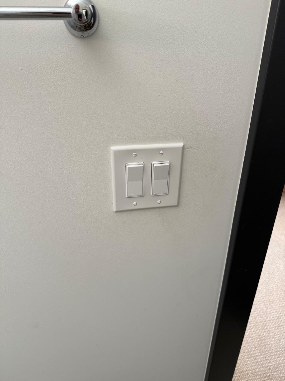 Finished two-gang rocker light switch installed flush and level on a hallway wall