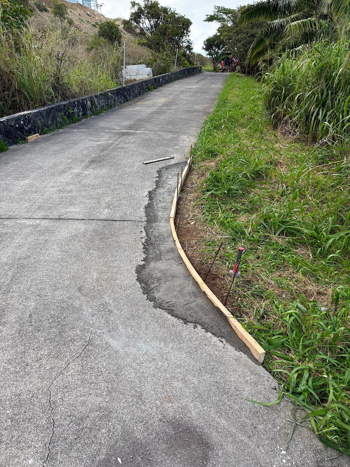 Paved roadway with a new wood curb form staked out along the shoulder, ready for a concrete pour